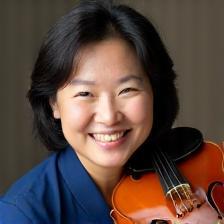 Teresa com violino no ombro e sorriso confiante